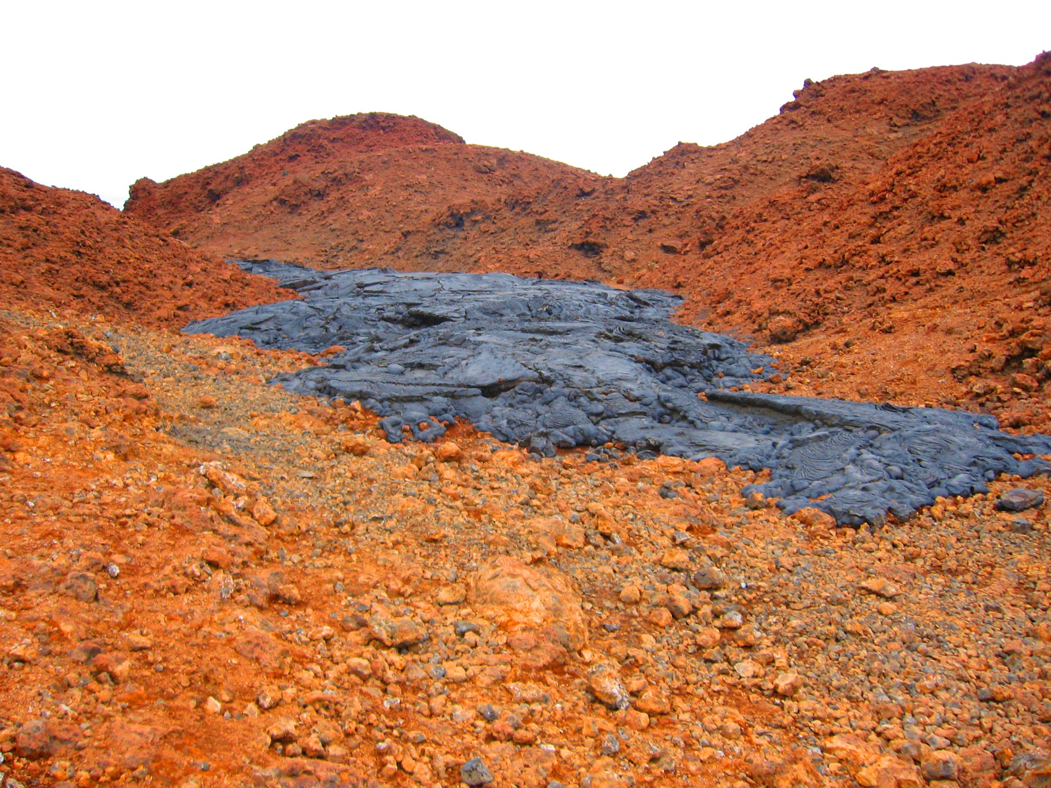 Young black lava flow surrounded by older red volcanic terrain at Sullivan Bay
